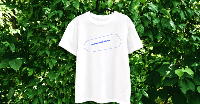 緑の葉を背景に掛けられたアストラカンの白いオリジナルTシャツ